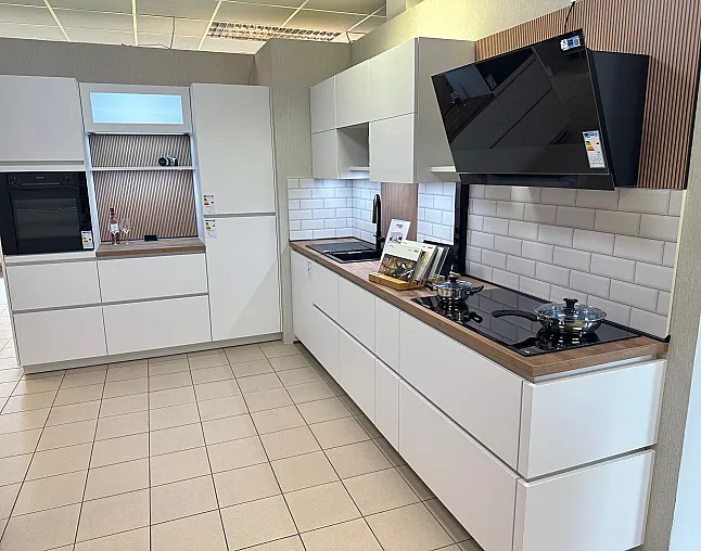 Moderne Küche mit weißen Schränken, schwarzen Kochplatten, Dunstabzugshaube, eingebautem Ofen und Spüle.