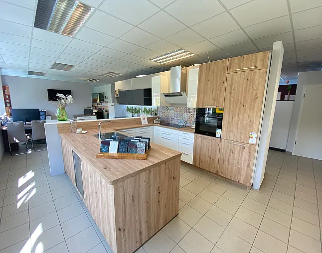 Moderne Kücheninsel und Holzschränke mit eingebautem Herd und Backofen in einem hellen Küchenstudio.