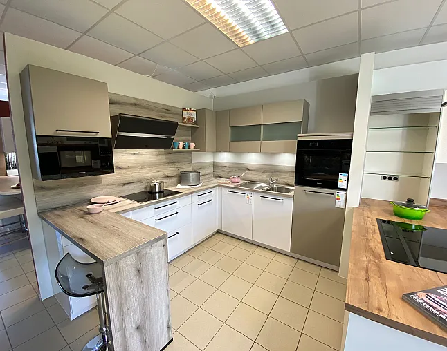 Moderne Küche mit L-förmigen Holzarbeitsplatten, eingebautem Backofen, Mikrowelle und Herd, hellem Fliesenspiegel und Hängeschränken.